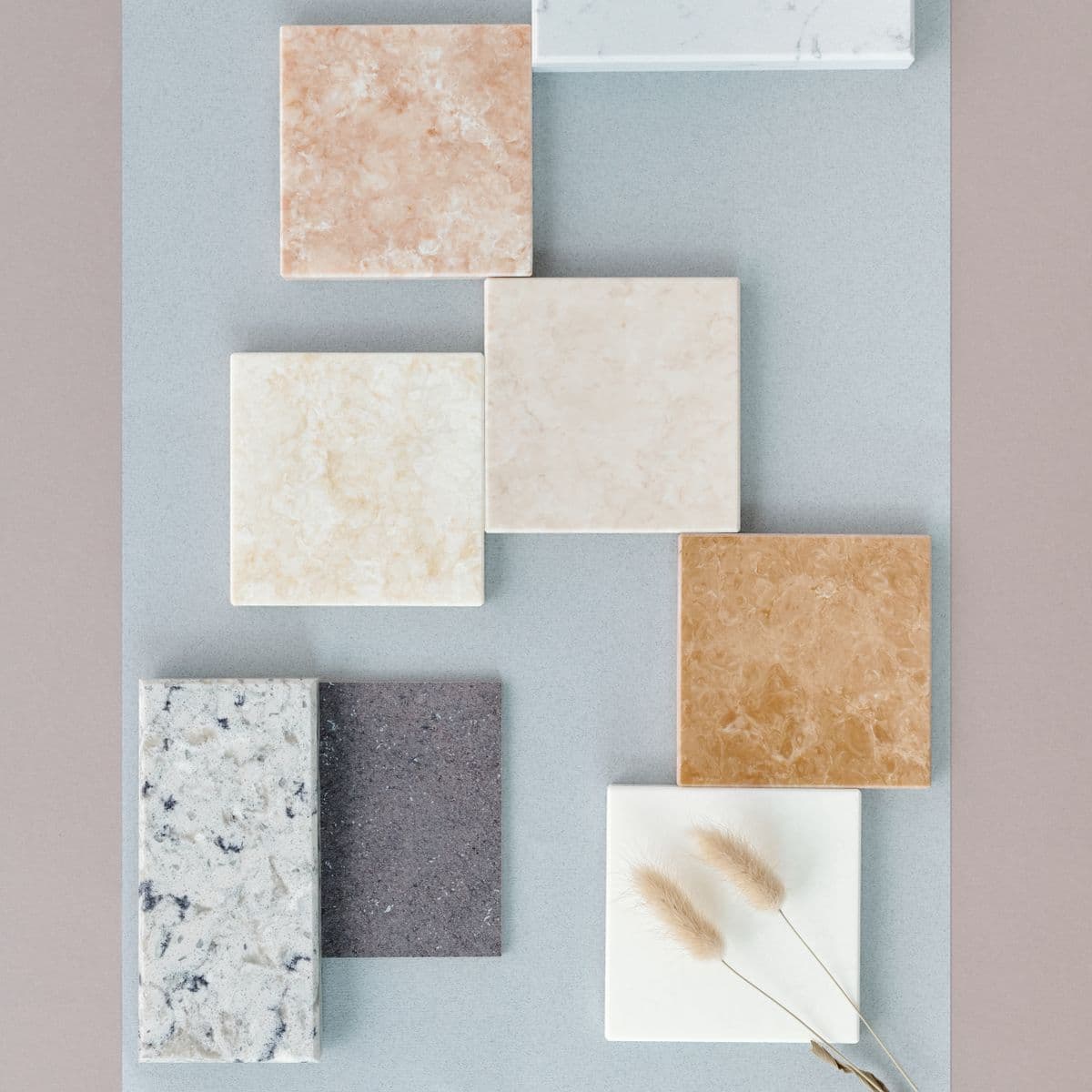 A flat-lay of stone and tile samples in warm neutral tones, arranged for material and finish selection.
